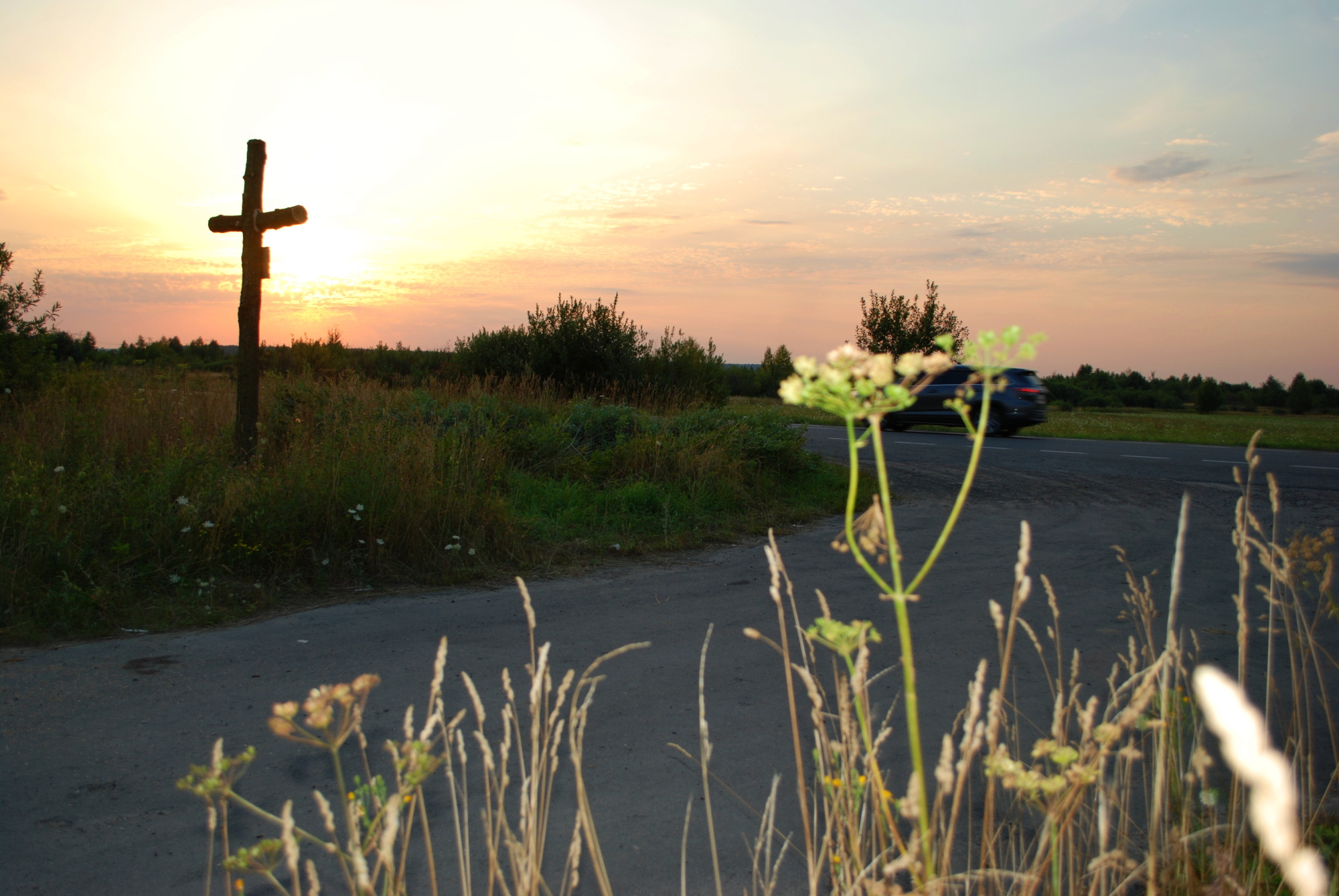 Widok krzyża na tle drogi.