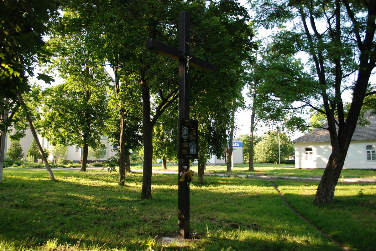 8. Widok na krzyż. Kościół stał z lewej strony, pomiędzy drzewami, tam widać budynek szpitala.